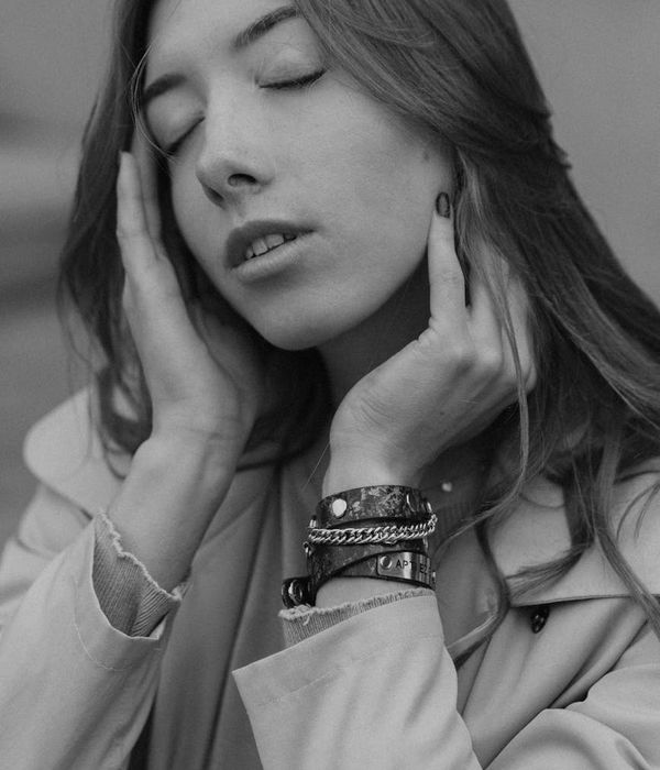 Woman in a calm yoga pose in a studio with soft cyan lighting.